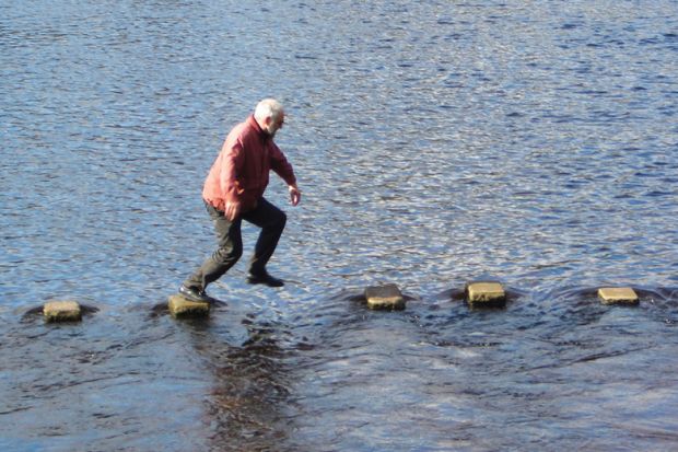 Man leaping across stepping stones in sea inlet