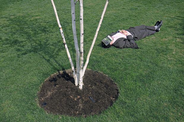 Man lying on the gras covering his face with a book