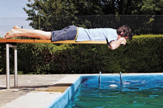 Man on diving board over swimming pool
