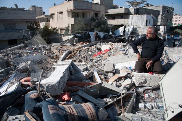 Man sits in rubble of Palestinian National Authority Council of Ministers building