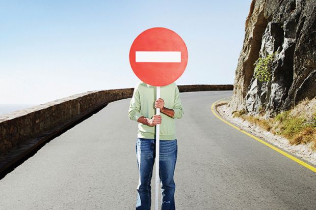 Man standing in road holding No Entry sign over face