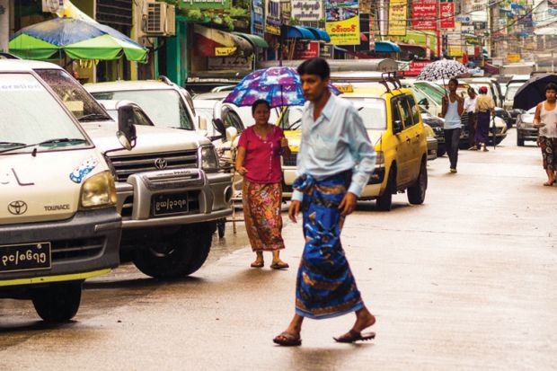 Man walking across congested street, Yangon, Myanmar