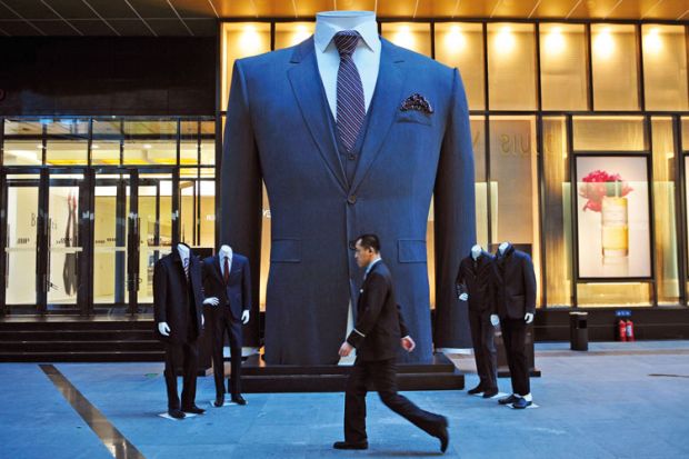 Man walks past huge suit, Shenyang, Liaoning province