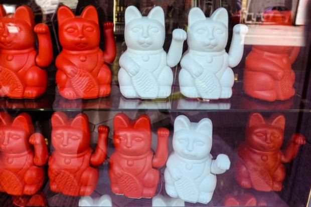 Maneki neko also known as chinese fortune cat. Showcase with welcoming souvenir cats beckoning to enter