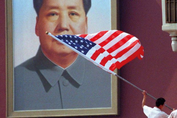 A worker installs an American flag in front of the portrait of China's late Chairman, Mao Zedong, which hangs on Tiananmen Gate in the centre of Beijing