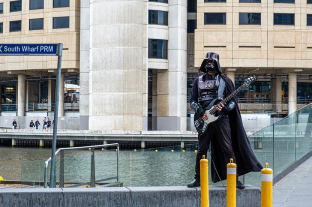 Melbourne, Australia - December 14, 2019 Street artist dressed as Darth Vader playing electric guitar