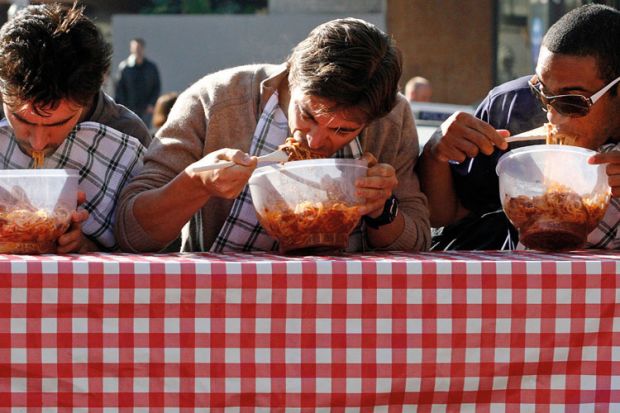 Men eating pasta in speed eating competition