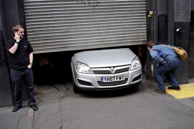 Men looking at car stuck under garage door