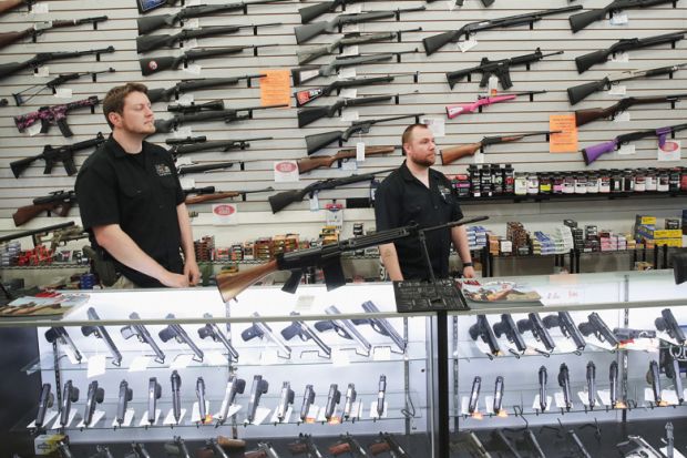 Men stand in front of display of firearms in gun store, Lake Barrington, Illinois