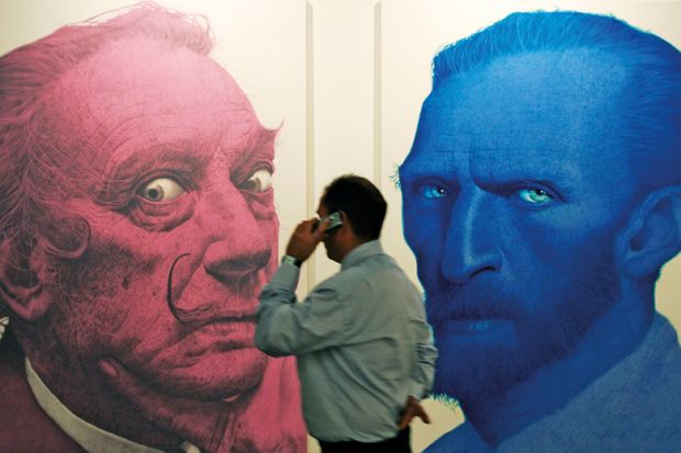 A man phones in front of portraits of the Salvador Dali (L) and Vincent Van Gogh (R) 