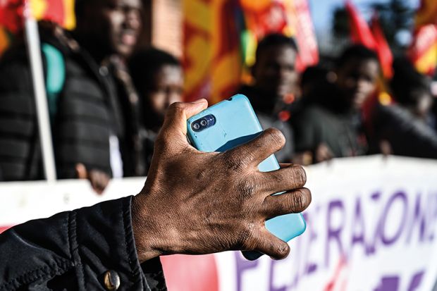 A migrant holds his mobile phone as members of anti-racism associations and migrants gather on Piazza della Repubblica in central Rome in December 2018 to protest the government’s decree restricting the right to asylum