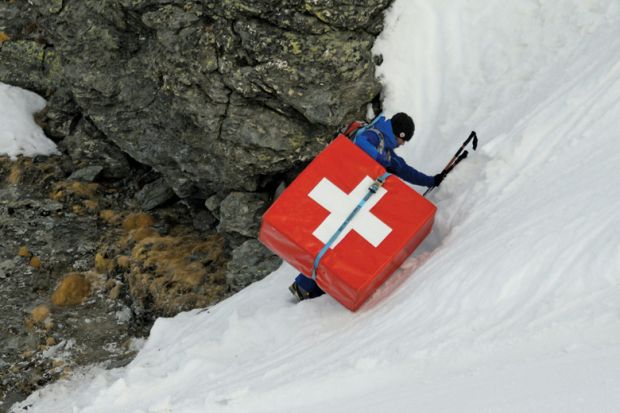 Mountain climber carrying safety mattress bearing Swiss flag