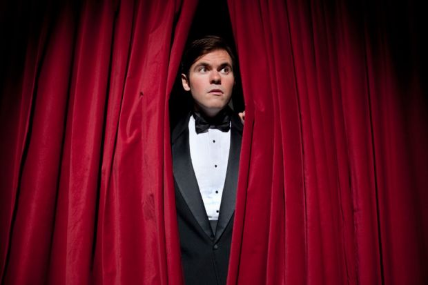 Nervous man peeking through stage curtains