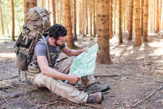 Outdoorsman/hiker sitting and reading map