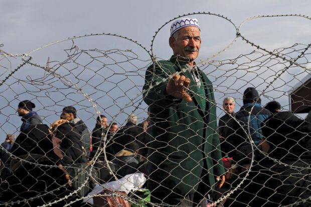 Palestinian man standing behind barbed fence, Gaza Strip, 2014