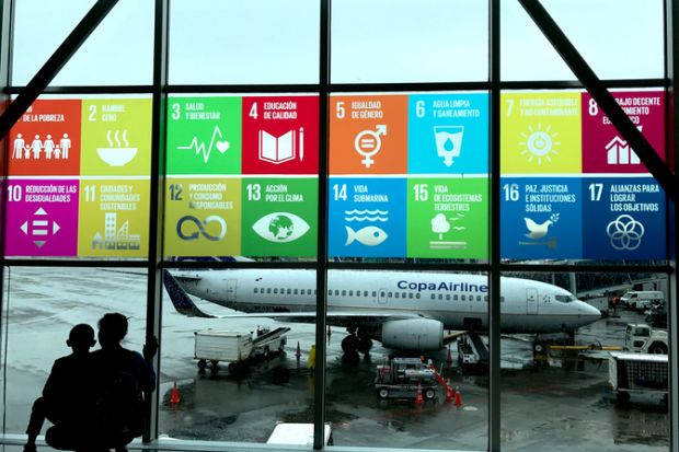 Panama CityPanama, October 18, 2018 The Global Goals displayed in Spanish on the windows at Panama City Tocumen International Airport. Mother and child looking out to see the planes.