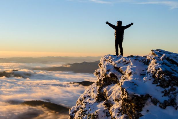 Person celebrating reaching top of mountain