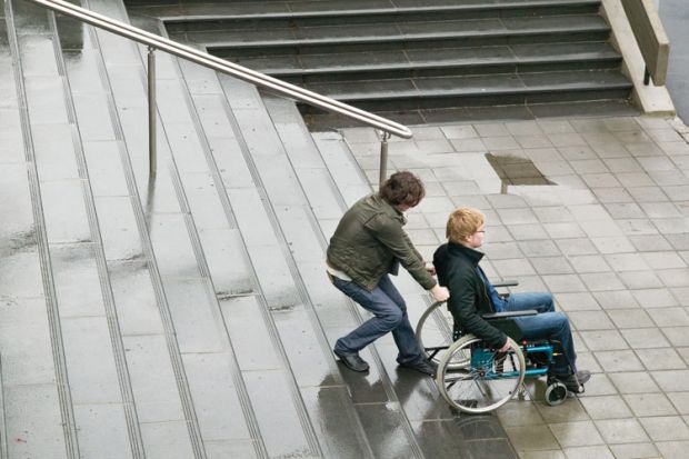 Person helping man in wheelchair up stairs