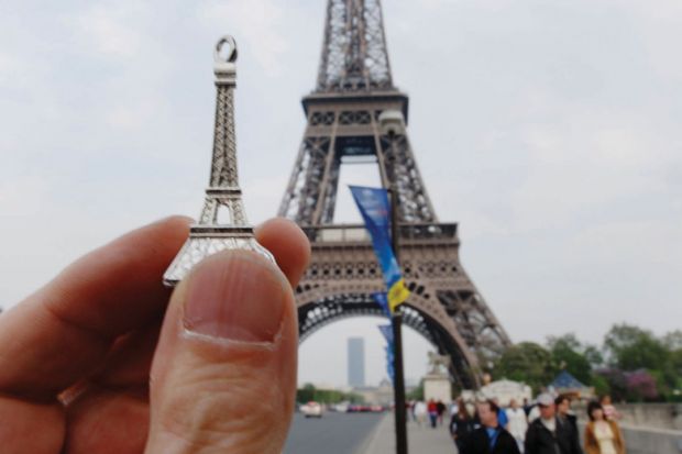 Person holding model in front of Eiffel Tower, Paris, France