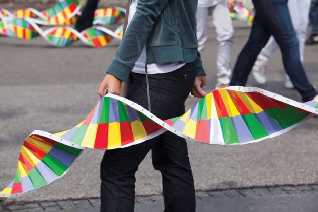 Person in street holding paper replica of DNA strand