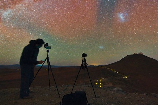 Person taking photographs of and recording night sky
