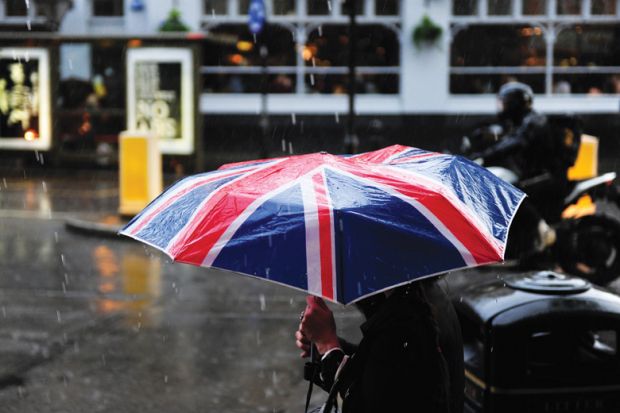 Person walking in rain carrying Union Jack umbrella