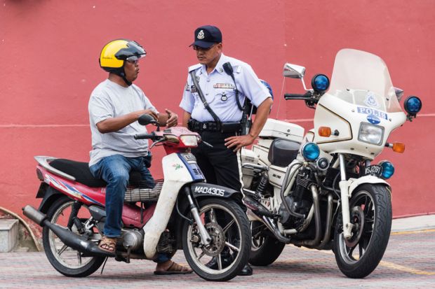 Policeman speaking to motorcyclist, Malacca, Malaysia