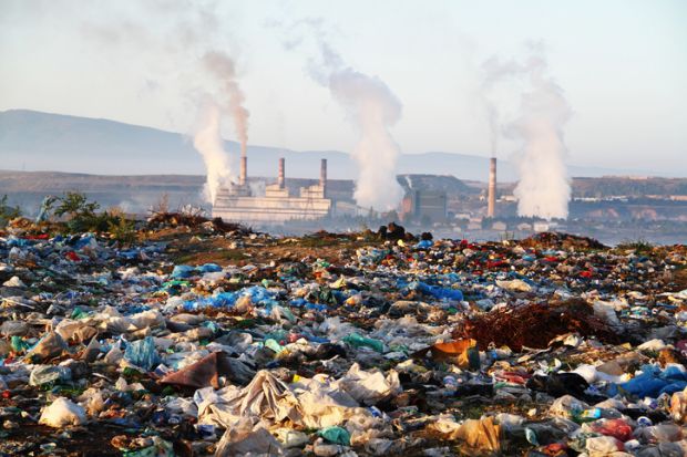Factory chimneys behind a rubbish dump, illustrating exploitative capitalism