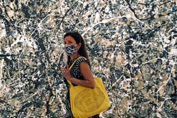 Woman in mask walking past a Pollock painting