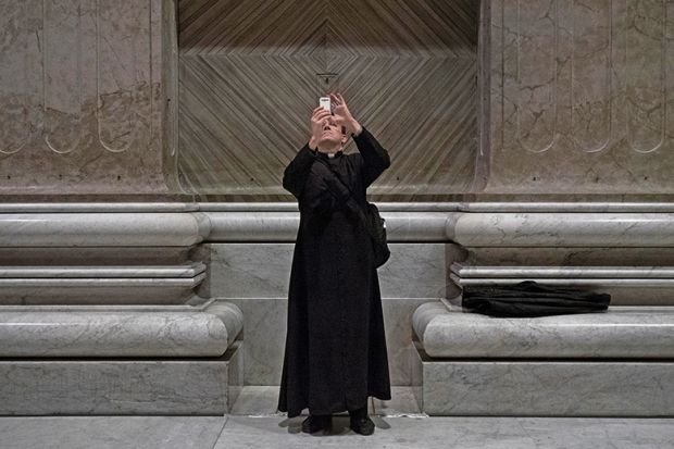 Priest taking photo with smartphone in church