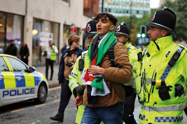 Police detain a man with a Palestine flag at a vigil for Israel held by Manchester Jewish Community in Manchester