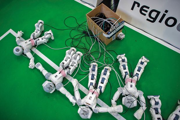 Robots charge by the play field at the 2013 RoboCup German Open tournament, illustrating an article about online cheating