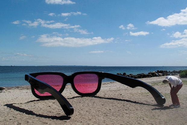 man looking through giant rose tinted sunglasses