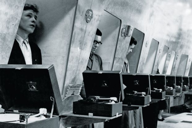 Row of men listening to vinyl records in turntable booths
