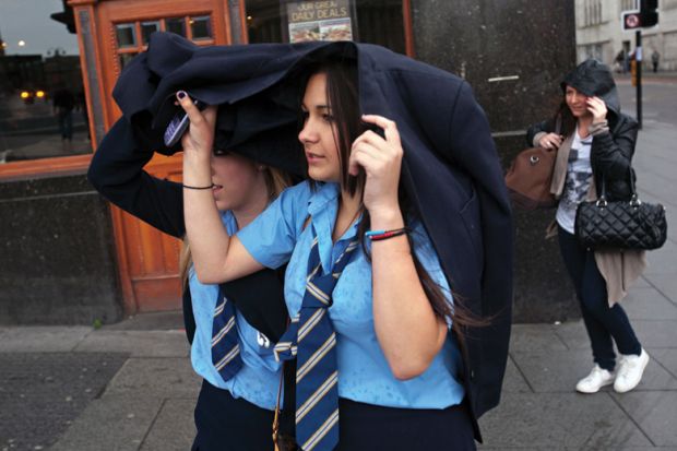 Schoolgirls shelter heads from rain, Liverpool