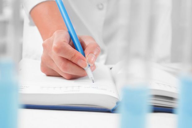 Scientist writing in notebook in laboratory