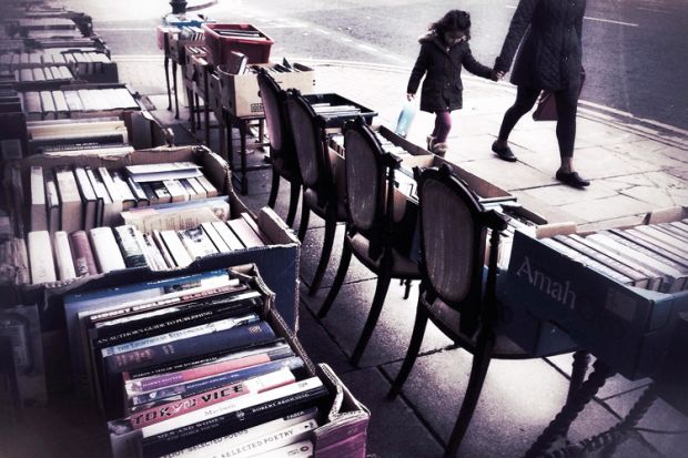 People walk past second hand books for sale