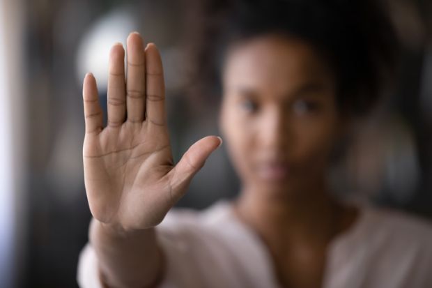 A woman holds up her hand, symbolising sexual harassment