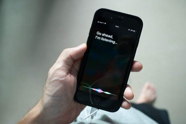 Siri, Apple's voice-activated digital assistant, tells iPhone user to ask her by showing the text Go ahead, I'm listening on the display.