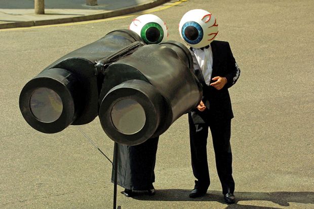 People dressed as eyeballs watch through giant pair of binoculars