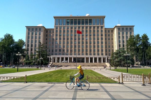 Students biking in front of the main entrance of the famous Tsinghua University building in Beijing