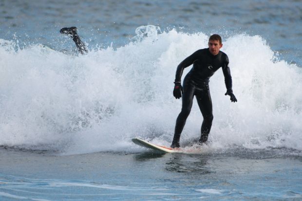 Surfer wiping out in small wave, Aberdeen Beach, Scotland