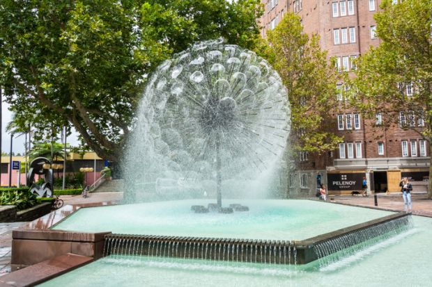 Sydney, Australia - March 10, 2017. El Alamein fountain at Fitzroy Gardens in Sydney, with commercial properties and people.