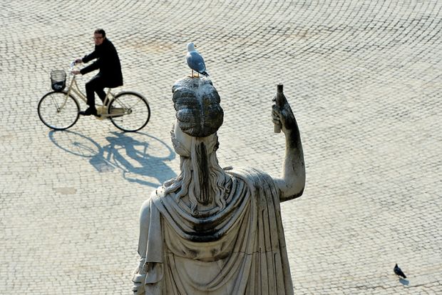 A man cycling past a statue in Rome