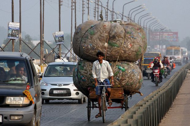 An Indian rickshaw puller transports discarded plastic bottles in Allahabad