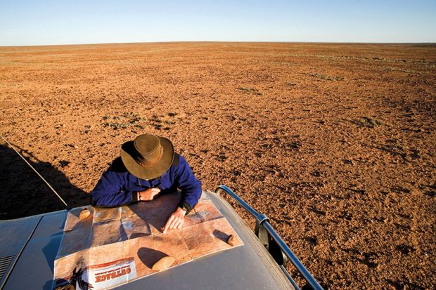 Man reading map on car bonnet in outback. Australia