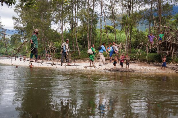 People cross a river in Papua New Guinea