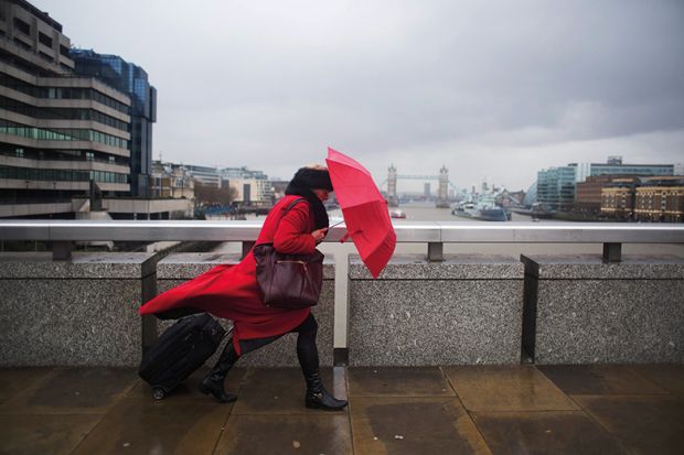 woman with umbrella walking across bridge, London