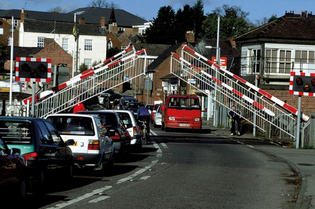 Barriers lifting at level crossing and waiting traffic streaming through