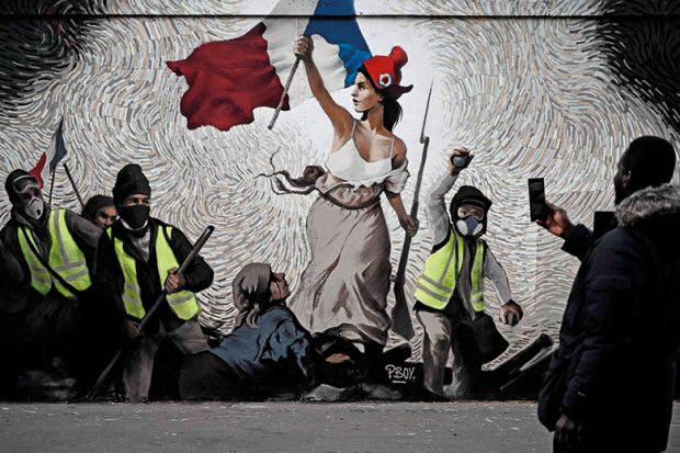 A man takes a picture of a mural by street artist PBOY depicting Yellow Vest (gilets jaunes) protestors inspired by "La Liberte guidant le Peuple" painting by Eugene Delacroix in Paris on January 8, 2019